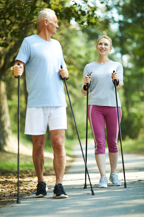 Active pensioners in sportswear trekking in park at leisure on summer day