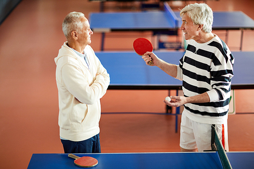 Annoyed ping pong trainer looking at mature player while explaining rules or details of game