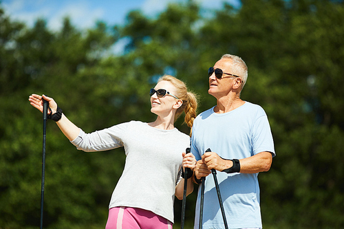 Active aged woman in sunglasses offering her husband to go trekking farther