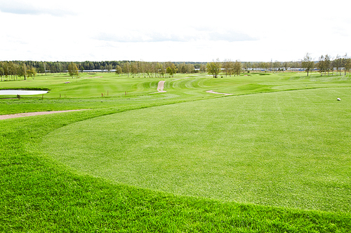 Vast green field for playing outdoor games such as golf and riverside surrounded by trees on background