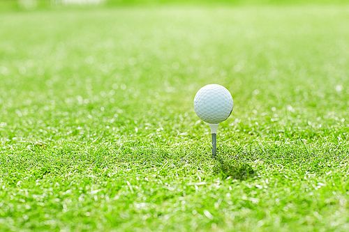 Golf ball on tee in the middle of green play field on sunny weekend before game