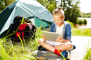 Young boy with tablet watching online videos while enjoying trip summer day