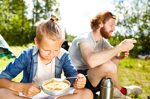 young boy and his father eating oat porridge for breakfast in the morning during their trip in natural