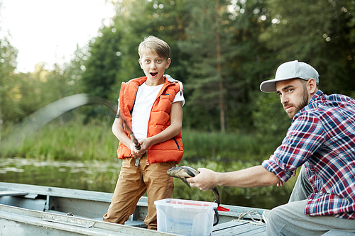 Amazed boy looking at bending rod while big fish in appearing in water