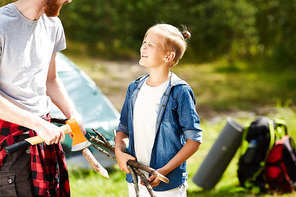 Little scout with sticks talking to his father during their trip on summer weekend