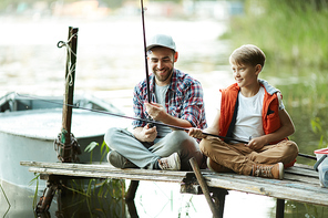 Father and his son spending time together during fishing on the lake