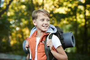 Young happy boy walking with backpack, having fun in summer forest