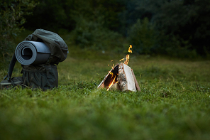 View of backpack and campfire in summer forest