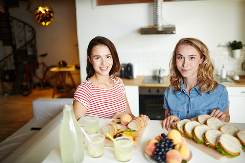 Two young friendly women  while preparing food for their guests in the kitchen