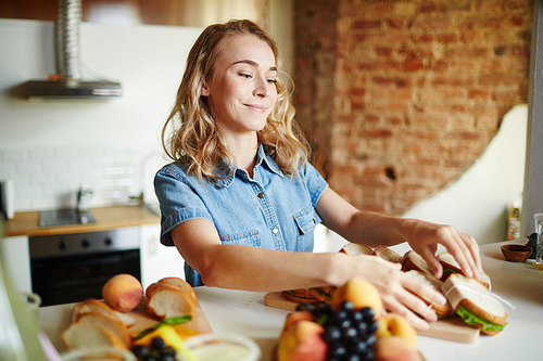 Happy girl preparing sandwiches for her guests at home