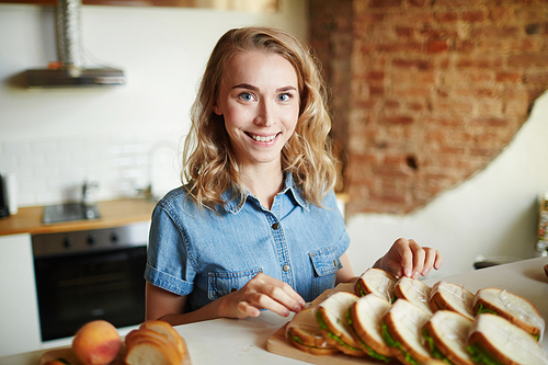 Happy young woman  while preparing homemade sandwiches