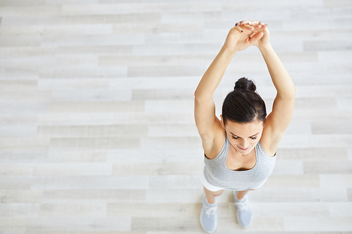 Young energetic and active female raising her arms while exercising in the morning