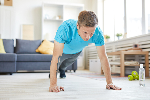 Young active man doing push-ups in the morning while staying at home