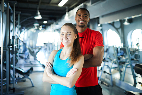 Young intercultural sports trainers of contemporary fitness center standing in front of camera