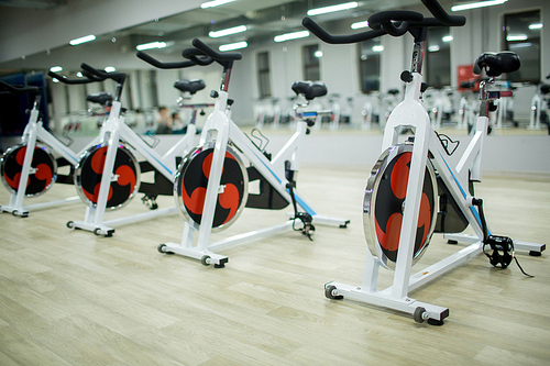 Row of new sports bikes for exercising in large modern fitness center or gym