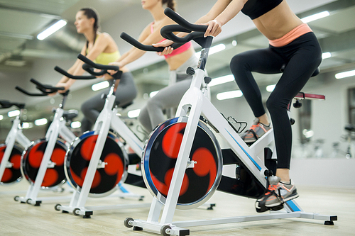 Row of active girls training on sports bikes in fitness center at leisure