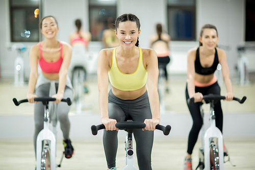 Successful young women in sportswear working out on sports training bikes at leisure center