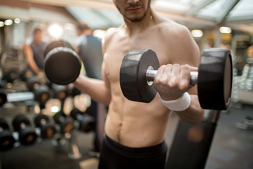Young shirtless athlete training with heavy barbells in contemporary sports club