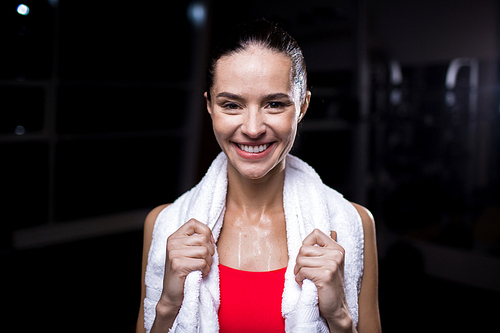 Wet young woman with white towel on her shoulders enjoying refreshment after hard workout