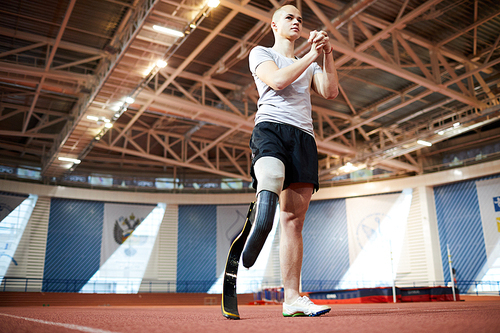 Paralympic sportsman doing exercise for hands during warm-up before training on stadium