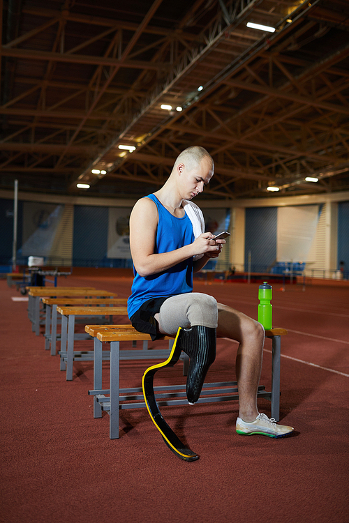 Restful guy in activewear having break after training on stadium before paralympic games