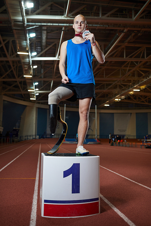 Young paralympic champion with medal standing on tribune in front of camera after games
