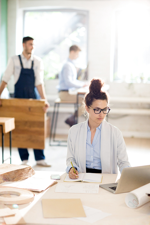 young female analyst sitting in front of laptop and solving organization moments in working