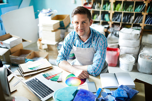 High angle portrait of modern artisan  and smiling while choosing color palette sitting at table in modern workshop, copy space