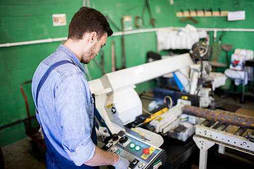 Young operator working on a lathe in the workshop machine factory