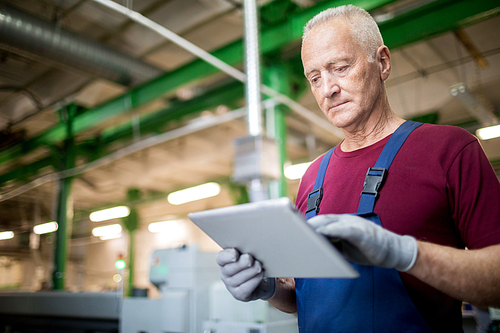 Mature professional worker using digital tablet at manufacturing plant