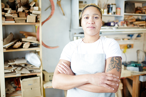 Female specialist in carpentry chores crossing her arms on chest and  in workshop