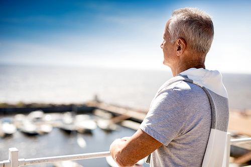 Aged man looking at deck while enjoying vacation by seaside in summer
