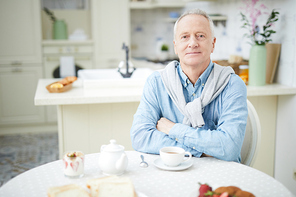 Happy senior man sitting by table served for tea and 