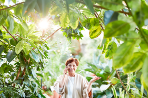 Happy aged woman decided to go for walk in her home garden or orangery while calling her children or husband