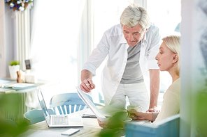 Confident senior man making presentation of some contract points to his colleague at start-up meeting