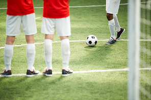 One of football players walking down green field after soccer ball during training before game