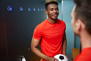 African-american guy in football uniform looking at his mate during their conversation in changing-room