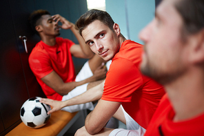 One of young footballers looking at his mate during break in changing-room after game