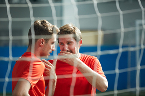 Two young footballers gossipping behind net after game of soccer in stadium