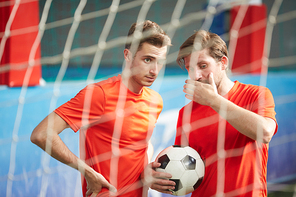 Two young men in uniform discussing mistakes that took place during game of soccer