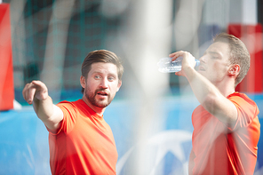 One of footballers pointing forwards while talking to his mate during refreshment