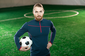 Young confident football trainer in sportswear  while standing on pitch