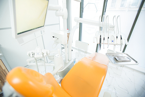 View of leather armchair for patients with monitor above and dentistry equipment in front