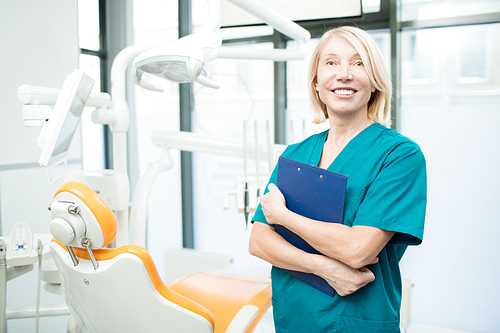 Mature female dentist or assistant with clipboard inviting you to new dental clinics