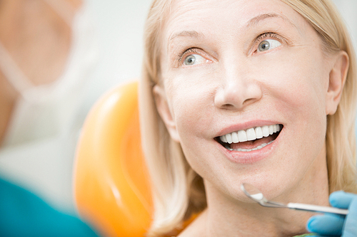 Happy patient with healthy teeth looking at dentist before check-up of oral cavity