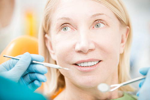 Aged woman listening to her dentist advice before or after check-up of oral cavity
