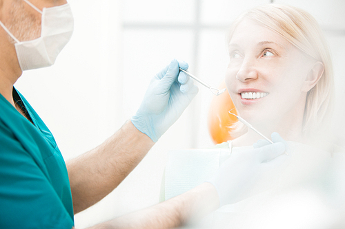 Smiling patient looking at her dentist in gloves and uniform before dental check-up