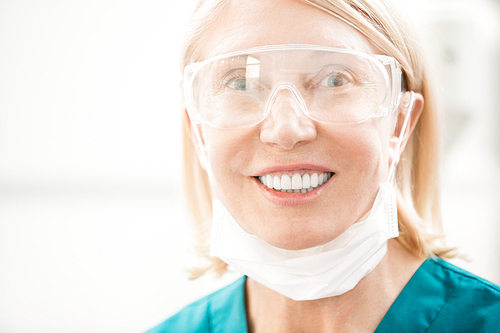 Successful surgeon or dentist in uniform and eyeglasses  with toothy smile