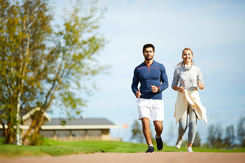 happy couple in activewear running together in natural  in the morning
