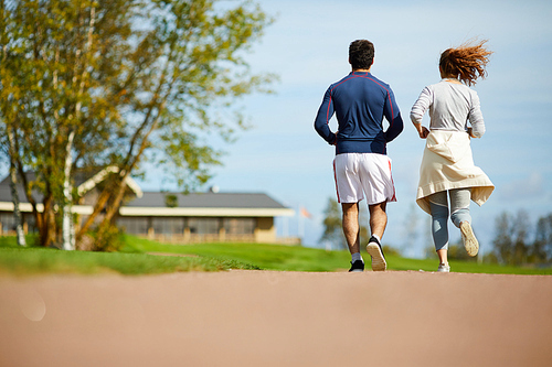 back view of young active couple jogging in rural  on summer morning